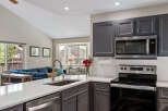 This modern kitchen features sleek gray cabinetry, a stainless steel microwave, and a smooth electric stovetop, perfect for any home chef.