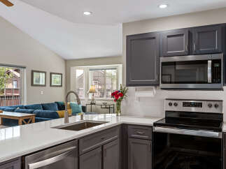 This modern kitchen features sleek gray cabinetry, a stainless steel microwave, and a smooth electric stovetop, perfect for any home chef.