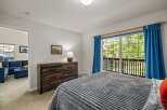 Experience comfort and style in this inviting bedroom, featuring a plush grey comforter on a spacious bed and a rustic wooden dresser.