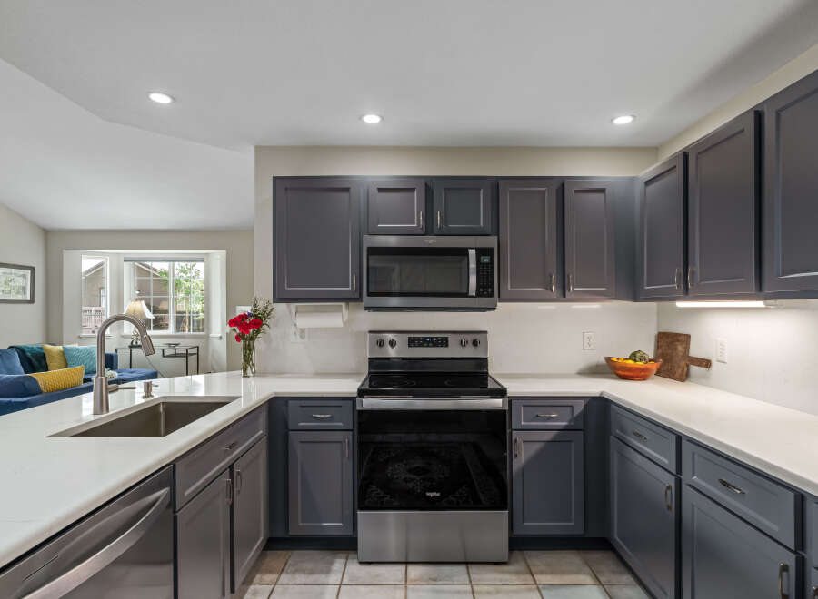 This modern kitchen boasts sleek, dark gray cabinetry complemented by a pristine white quartz countertop.