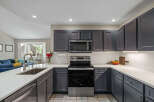 This modern kitchen boasts sleek, dark gray cabinetry complemented by a pristine white quartz countertop.