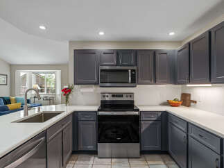 This modern kitchen boasts sleek, dark gray cabinetry complemented by a pristine white quartz countertop.