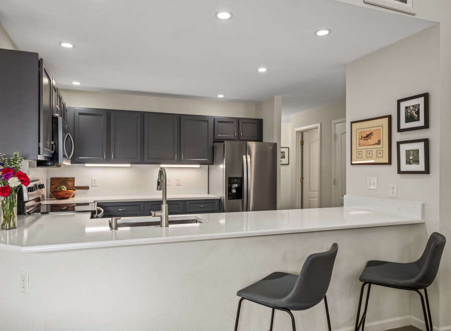 Discover this beautifully updated kitchen featuring sleek dark gray cabinetry and modern quartz countertops.