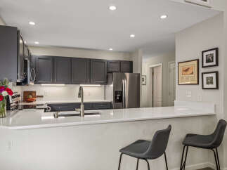 Discover this beautifully updated kitchen featuring sleek dark gray cabinetry and modern quartz countertops.