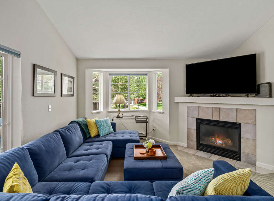 Cozy up by the fireplace in this inviting living room, featuring a plush blue sectional sofa perfect for relaxation.