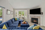 Cozy up by the fireplace in this inviting living room, featuring a plush blue sectional sofa perfect for relaxation.
