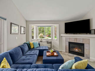 Cozy up by the fireplace in this inviting living room, featuring a plush blue sectional sofa perfect for relaxation.