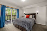 This inviting bedroom features a spacious bed with a plush grey comforter and decorative pillows, including a vibrant orange accent pillow.