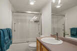 This bright and clean bathroom features a spacious bathtub with a sliding glass shower door and white tiled walls.