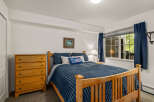 This charming bedroom features a comfortable queen-size bed with plush blue bedding, complemented by a wooden dresser with vibrant blue knobs.