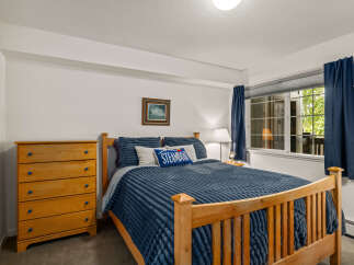 This charming bedroom features a comfortable queen-size bed with plush blue bedding, complemented by a wooden dresser with vibrant blue knobs.