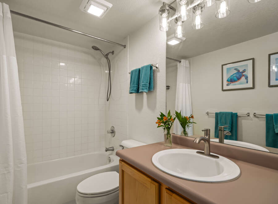 This bathroom features a clean and bright aesthetic with white tiled walls and a classic white bathtub.