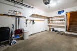 This garage offers ample storage with multiple shelves and a wall-mounted rack system, perfect for organizing tools and equipment.