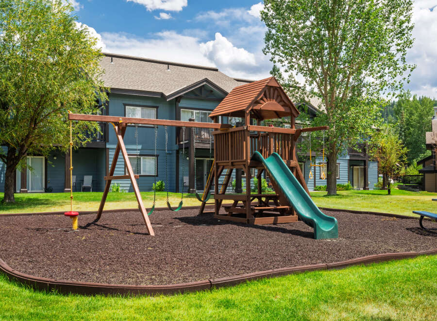 Enjoy outdoor fun with this fantastic playground featuring swings, a slide, and a rope swing, all set on a soft, wood-chip surface.