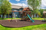 Enjoy outdoor fun with this fantastic playground featuring swings, a slide, and a rope swing, all set on a soft, wood-chip surface.
