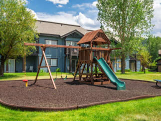 Enjoy outdoor fun with this fantastic playground featuring swings, a slide, and a rope swing, all set on a soft, wood-chip surface.