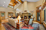 Experience rustic elegance in this spacious living room, featuring a grand stone fireplace and soaring vaulted ceilings with exposed wooden beams.