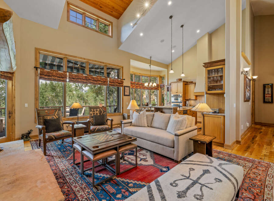 Experience luxury living in this stunning great room, featuring a soaring vaulted ceiling with exposed wood beams and a grand stone fireplace.