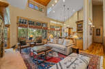 Experience luxury living in this stunning great room, featuring a soaring vaulted ceiling with exposed wood beams and a grand stone fireplace.