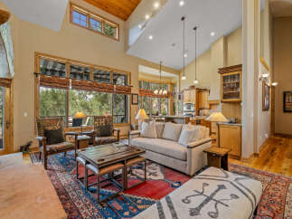 Experience luxury living in this stunning great room, featuring a soaring vaulted ceiling with exposed wood beams and a grand stone fireplace.