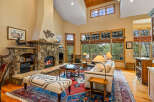 Experience rustic elegance in this spacious living room, featuring a grand stone fireplace and soaring vaulted ceilings with exposed wood beams.