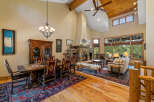 Experience rustic elegance in this spacious living and dining area, featuring a grand stone fireplace and soaring vaulted ceilings with exposed wooden beams.