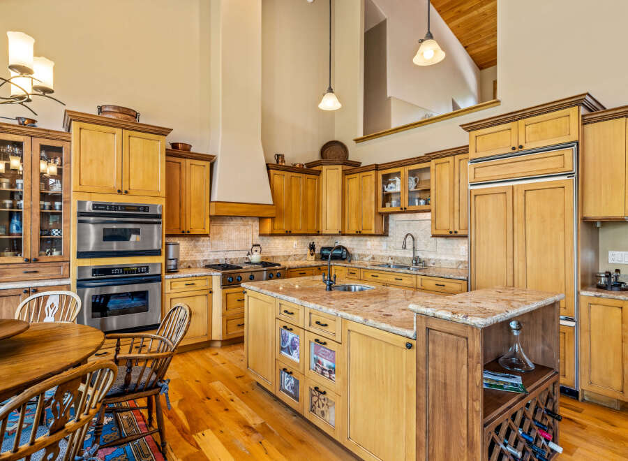 Experience culinary excellence in this spacious gourmet kitchen, featuring custom wood cabinetry, granite countertops, and a large central island perfect for meal prep and entertaining.