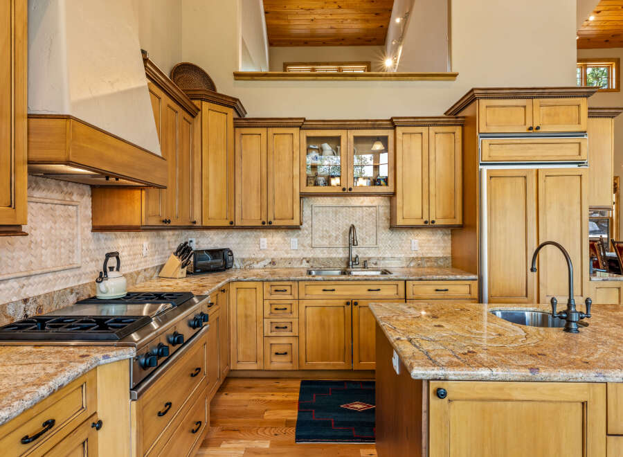 This spacious kitchen boasts custom light wood cabinetry, granite countertops, and a large island perfect for entertaining.