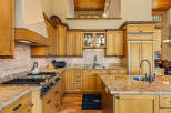 This spacious kitchen boasts custom light wood cabinetry, granite countertops, and a large island perfect for entertaining.
