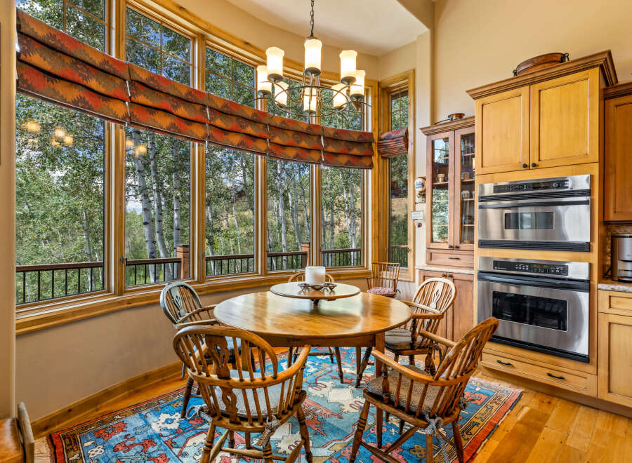 Enjoy breathtaking forest views from this charming dining area, featuring a round wooden table and comfortable chairs perfect for intimate gatherings.