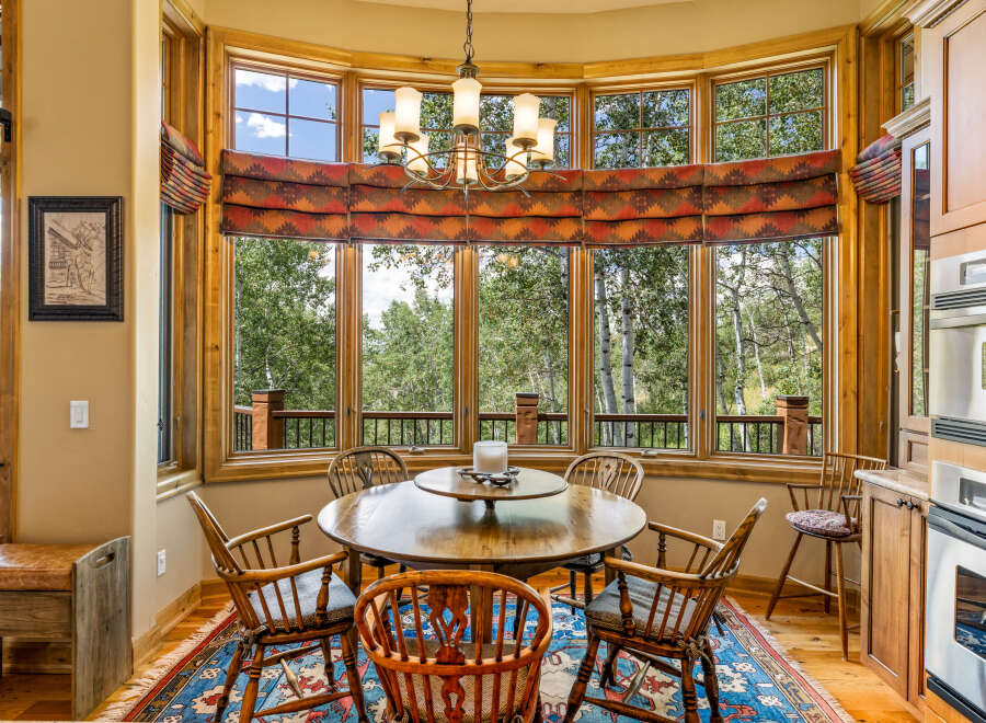 Enjoy breathtaking mountain views from this charming dining nook, featuring a round wooden table surrounded by classic Windsor chairs.