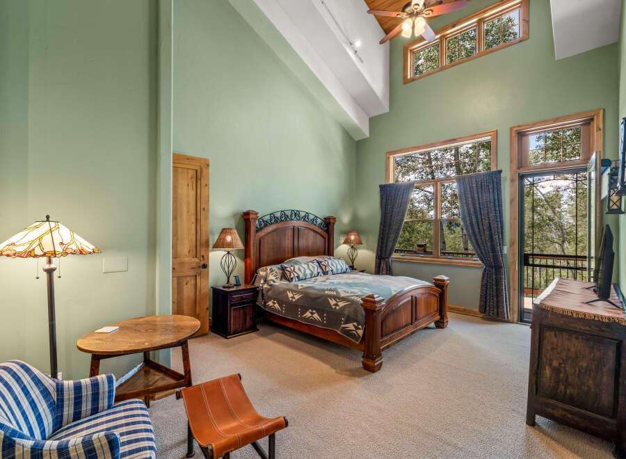 Experience rustic charm in this spacious bedroom featuring a grand wooden bed and vaulted ceilings with exposed beams.