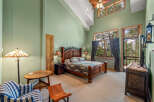 Experience rustic charm in this spacious bedroom featuring a grand wooden bed and vaulted ceilings with exposed beams.