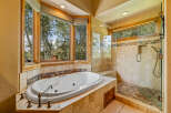Indulge in relaxation in this luxurious bathroom featuring a spacious corner soaking tub with stunning views of the surrounding trees.