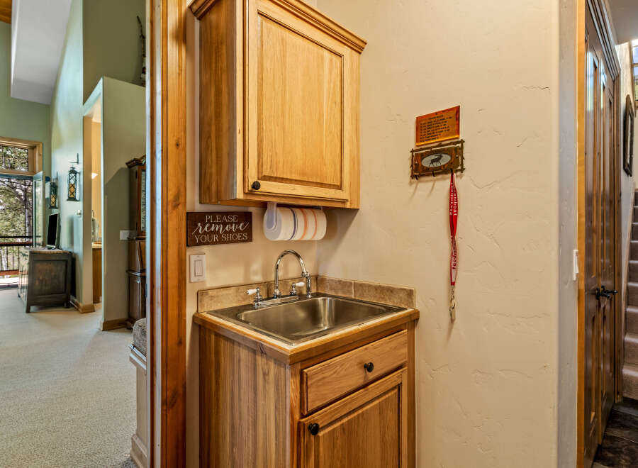 Welcome guests with a charming entryway featuring a convenient sink and cabinetry, perfect for a quick hand wash or storing essentials.