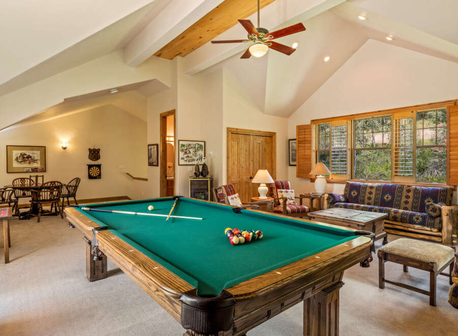Enjoy endless entertainment in this spacious game room, featuring a full-size pool table and a cozy seating area.