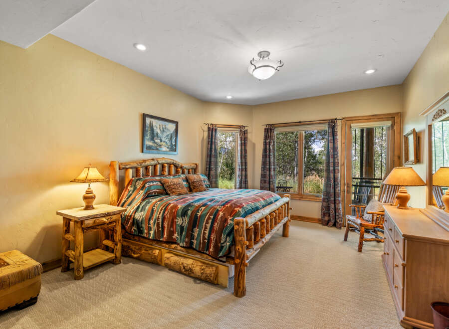 Experience rustic charm in this inviting bedroom, featuring a sturdy log bed adorned with a vibrant, patterned comforter.