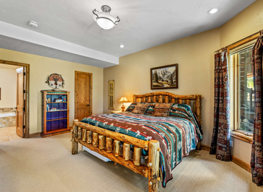Experience rustic charm in this inviting bedroom, featuring a unique log bed and a cozy mountain-themed comforter.
