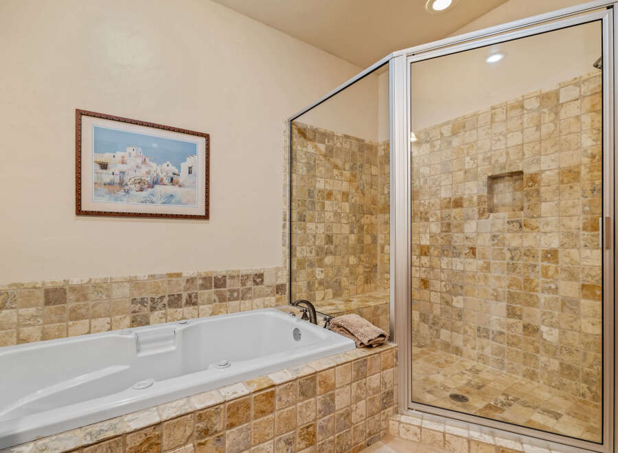 Indulge in relaxation in this luxurious bathroom featuring a spacious soaking tub and a separate glass-enclosed shower.