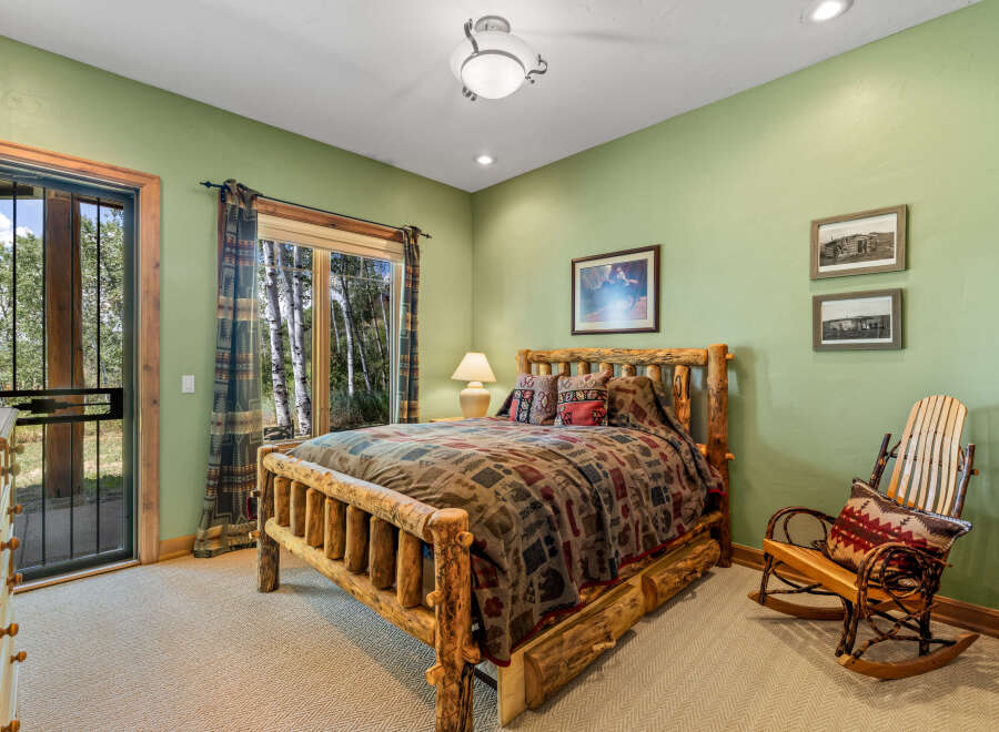 Experience rustic charm in this cozy bedroom featuring a handcrafted log bed and a comfortable rocking chair.