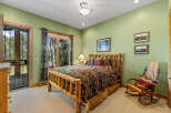 Experience rustic charm in this cozy bedroom featuring a handcrafted log bed and a comfortable rocking chair.