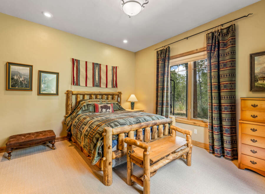 Experience rustic charm in this cozy bedroom featuring a log-frame bed adorned with a nature-inspired comforter and accent pillows.