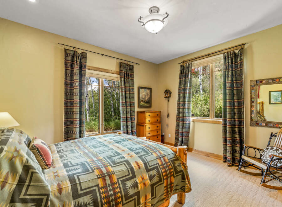 Experience rustic charm in this cozy bedroom, featuring a comfortable bed adorned with a patterned blanket and accent pillows.
