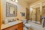 This charming bathroom features a wood vanity with a tiled countertop and a white porcelain sink.
