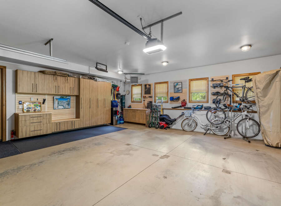 This spacious garage offers ample storage with custom wooden cabinetry and a pegboard system for organizing tools and equipment.