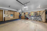 This spacious garage offers ample storage with custom wooden cabinetry and a pegboard system for organizing tools and equipment.