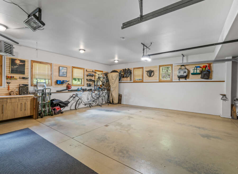 This spacious garage offers ample storage and organization solutions, featuring custom cabinetry, slatted wall panels for versatile hanging options, and overhead storage.