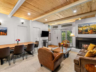 Experience cozy mountain living in this inviting living space featuring a warm fireplace and a rustic wooden dining table perfect for family gatherings.