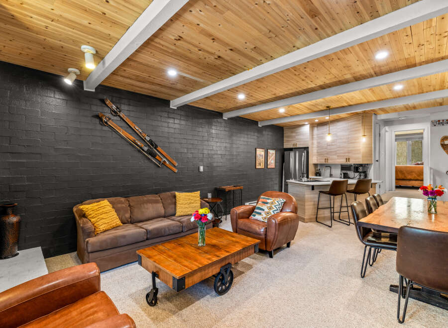 Experience rustic charm in this mountain retreat, featuring a cozy living area with a dark brick accent wall and vintage skis.