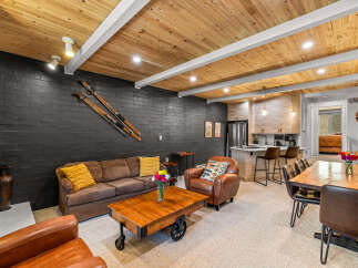 Experience rustic charm in this mountain retreat, featuring a cozy living area with a dark brick accent wall and vintage skis.